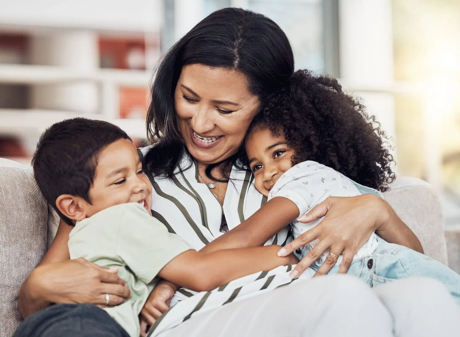 An adult sits on a couch with two children.