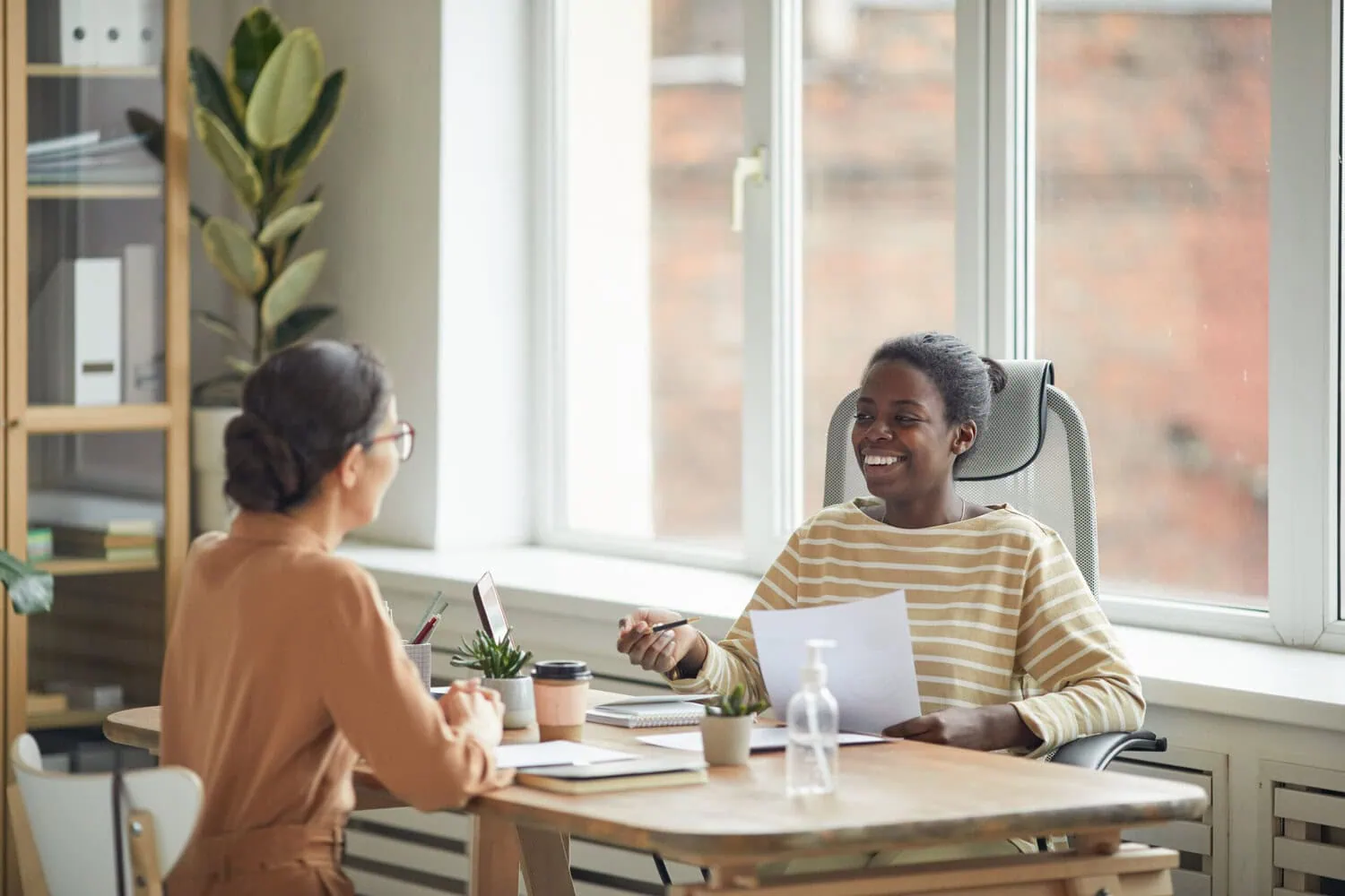 Two adults meet at a table in an office.