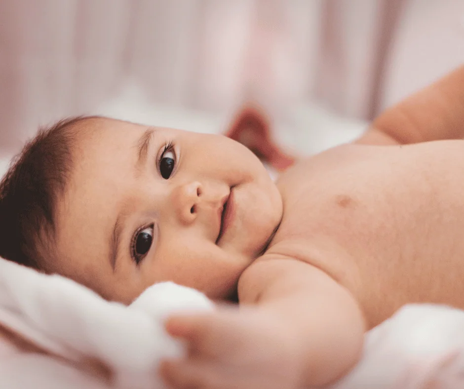 A baby rests on a white blanket.