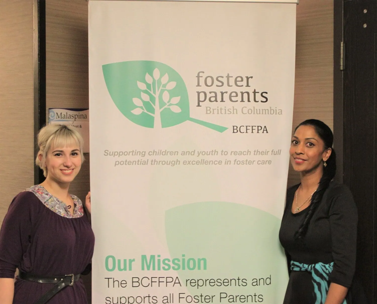 Two people stand beside a BCFPA banner at an event.