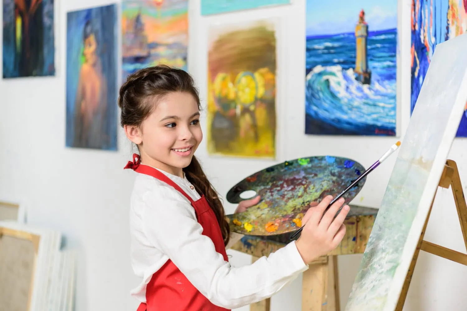 A child paints on a canvas in an art studio.