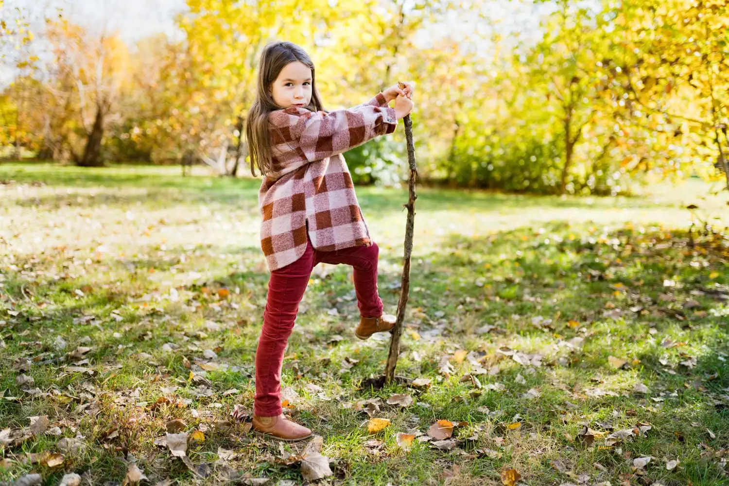 A child plays outdoors with a stick.