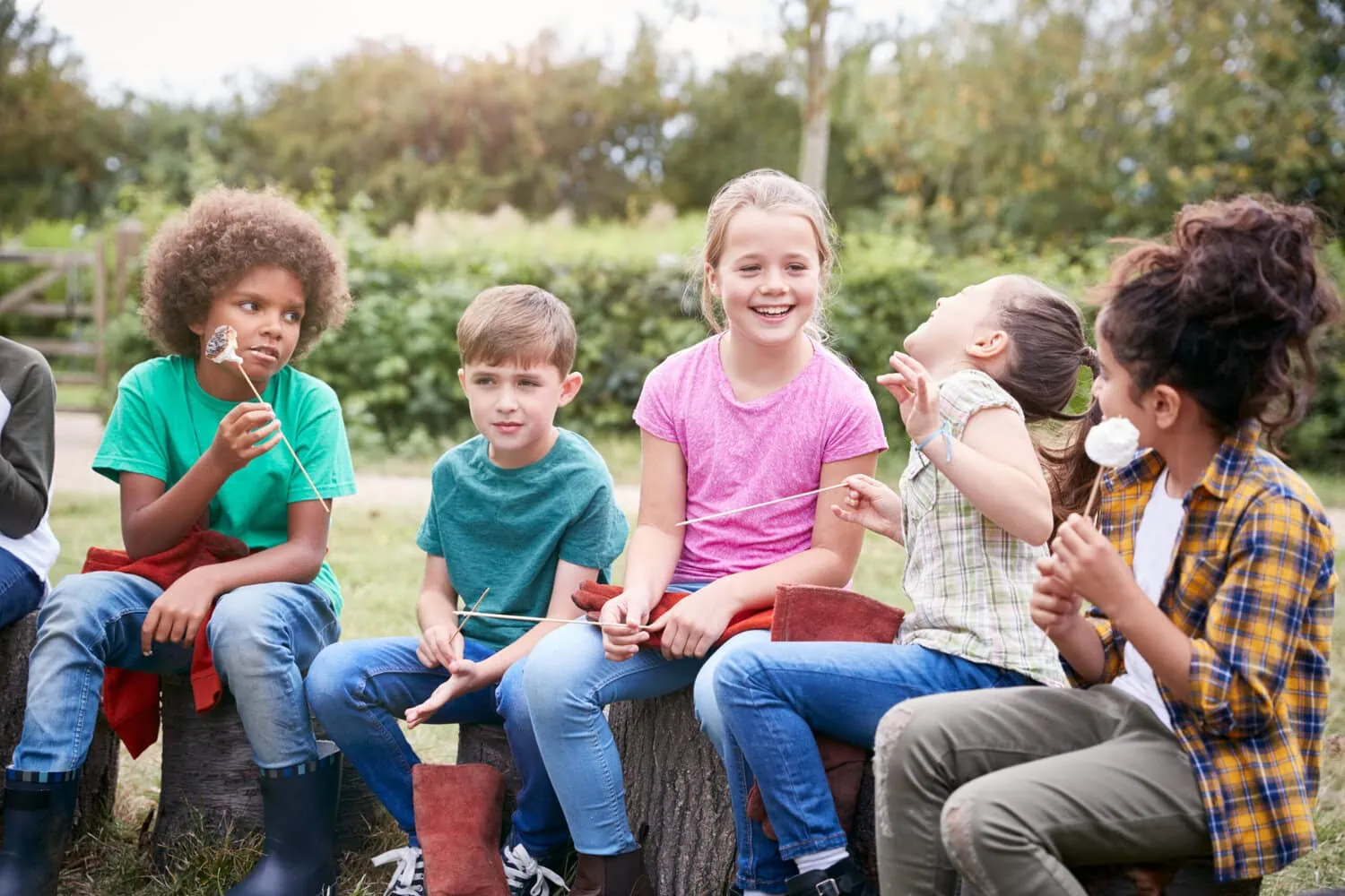 A group of children sit outdoors with snacks.
