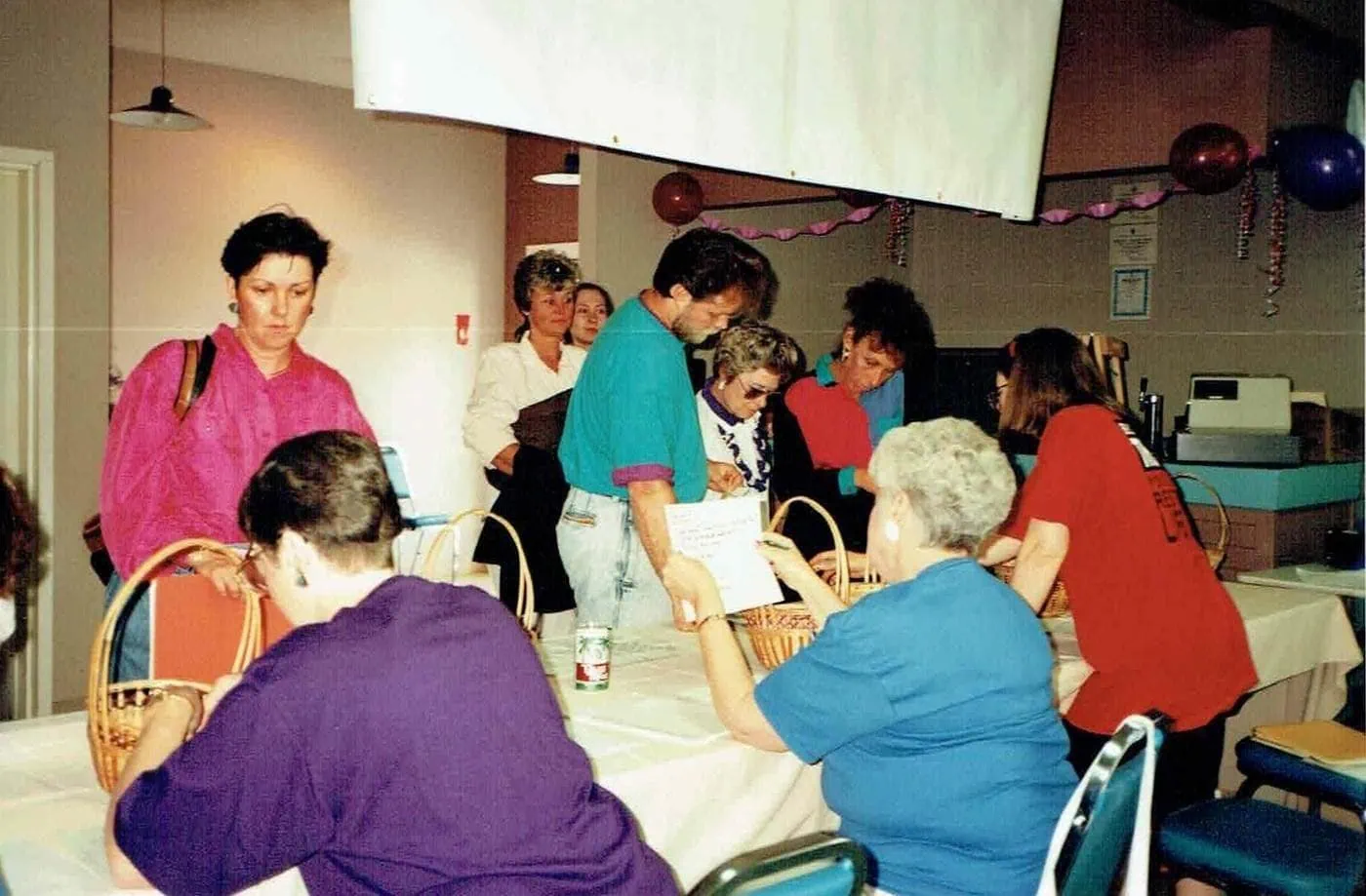 Foster parents and caregivers gather around tables at a historical meeting.