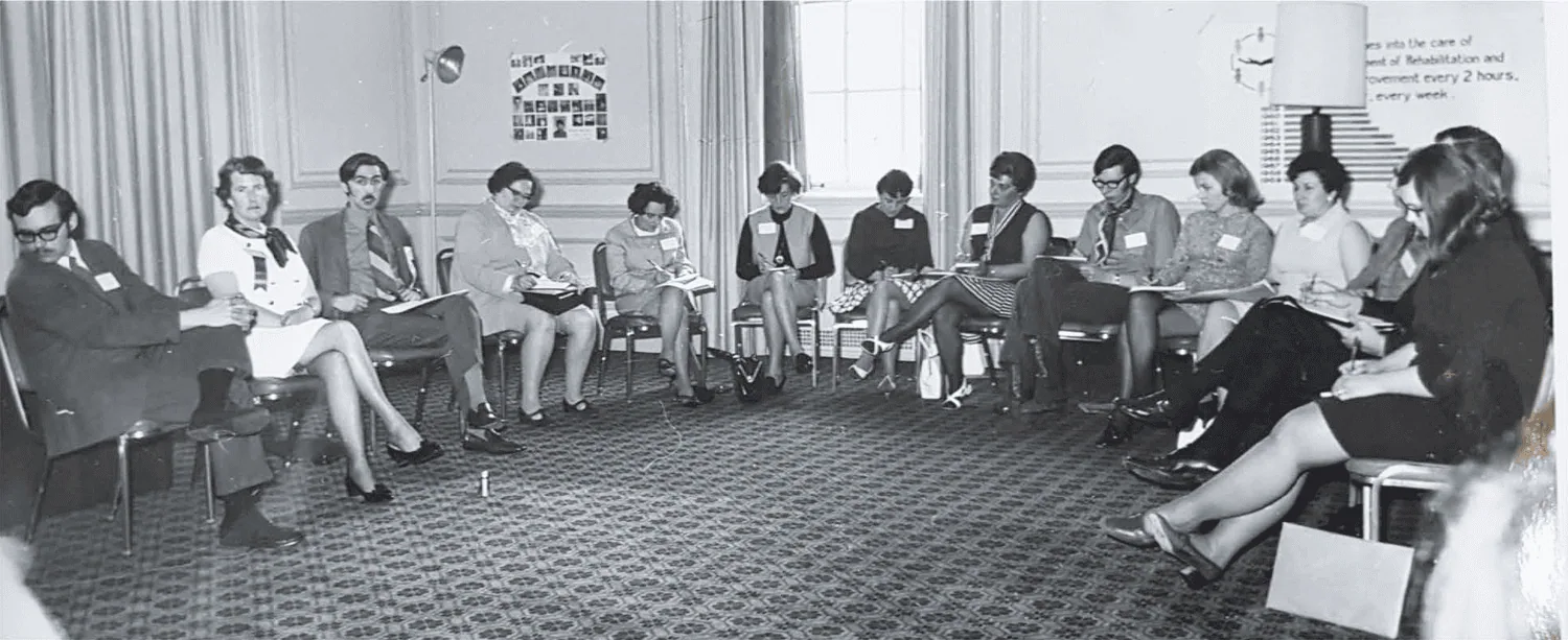 Black-and-white photograph of foster parents seated in a circle during a meeting.