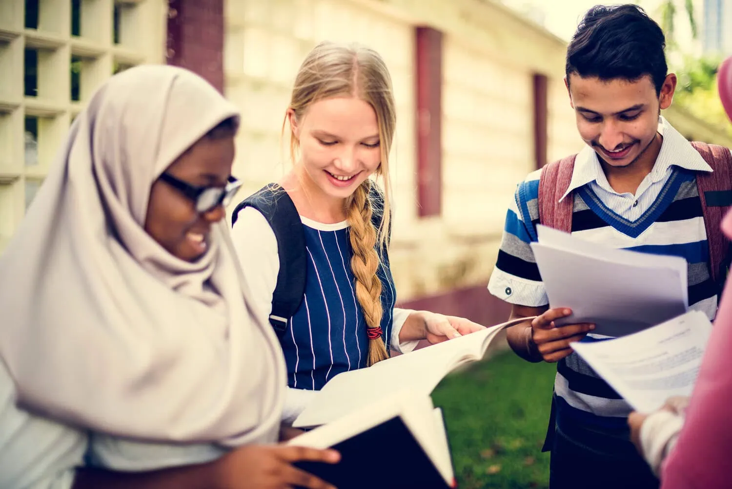 A group of students reviews papers together outdoors.