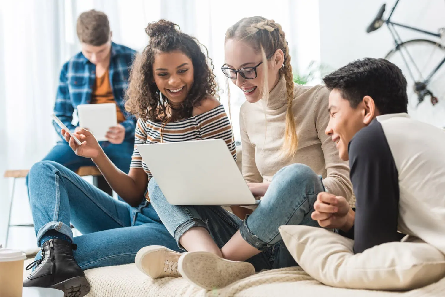 Four students study together with a laptop and tablet.