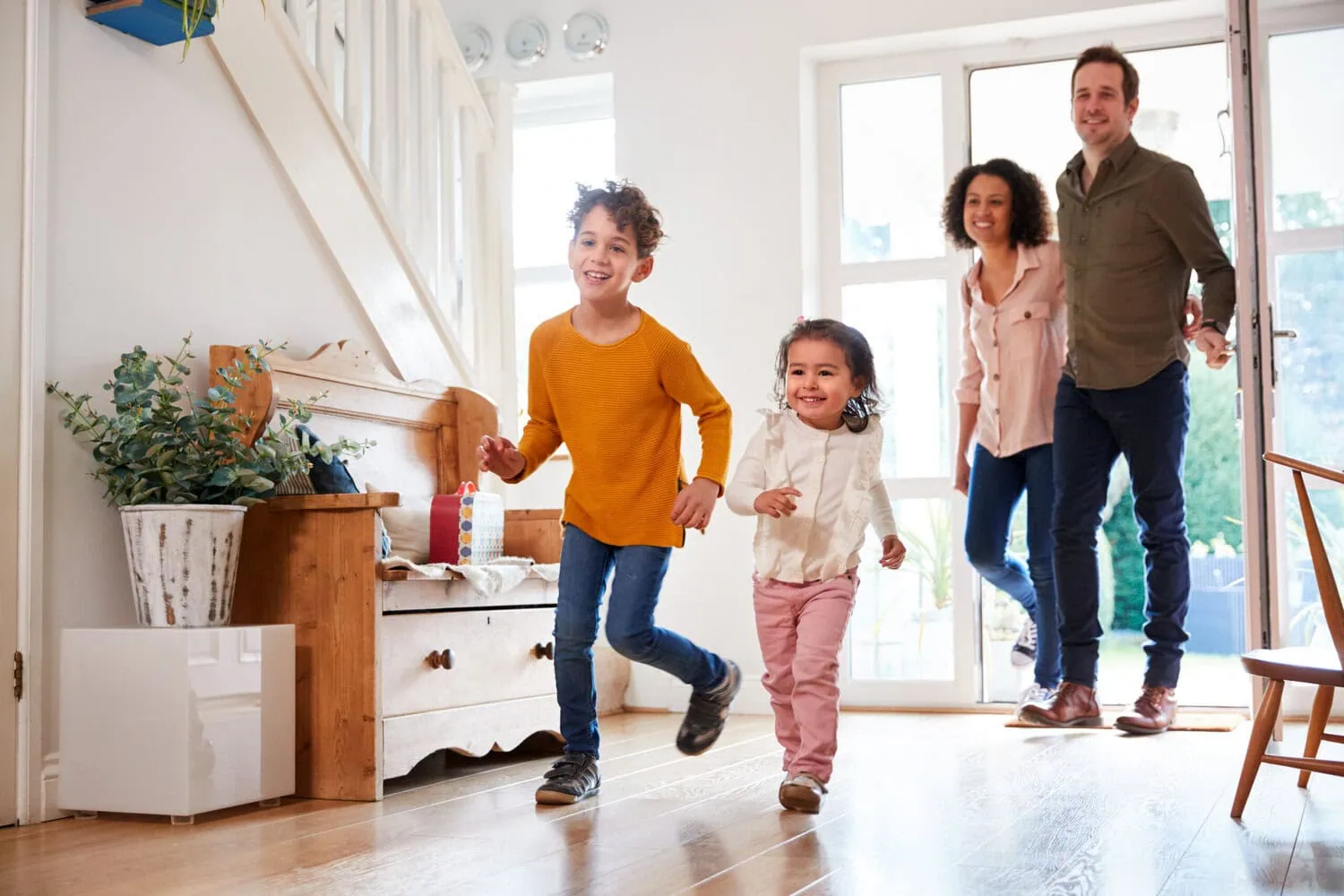 Two children run into a home as two adults follow them inside.